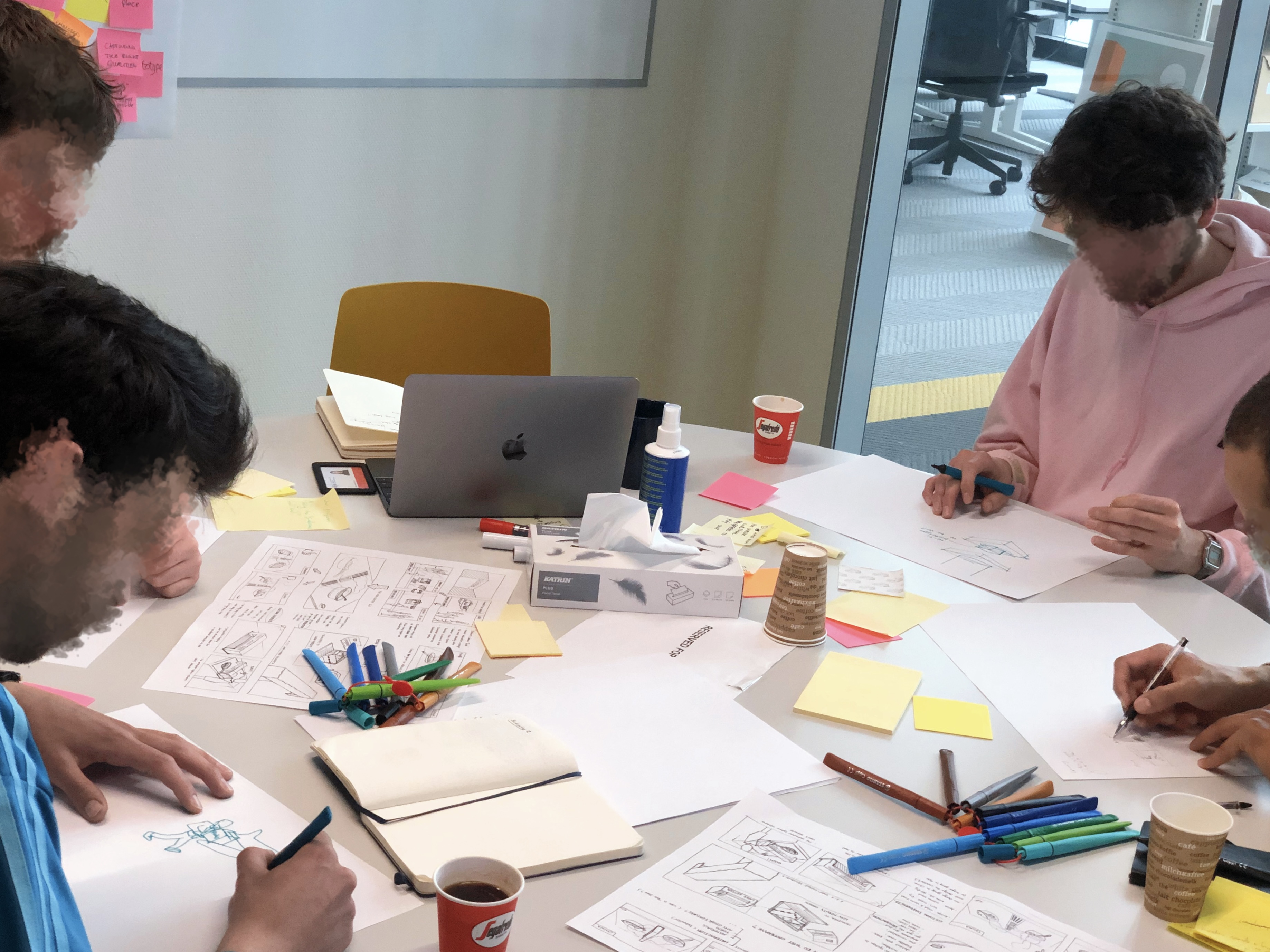 Two student teams sketching and ideating together around a table during a Constructive Design Research coaching session